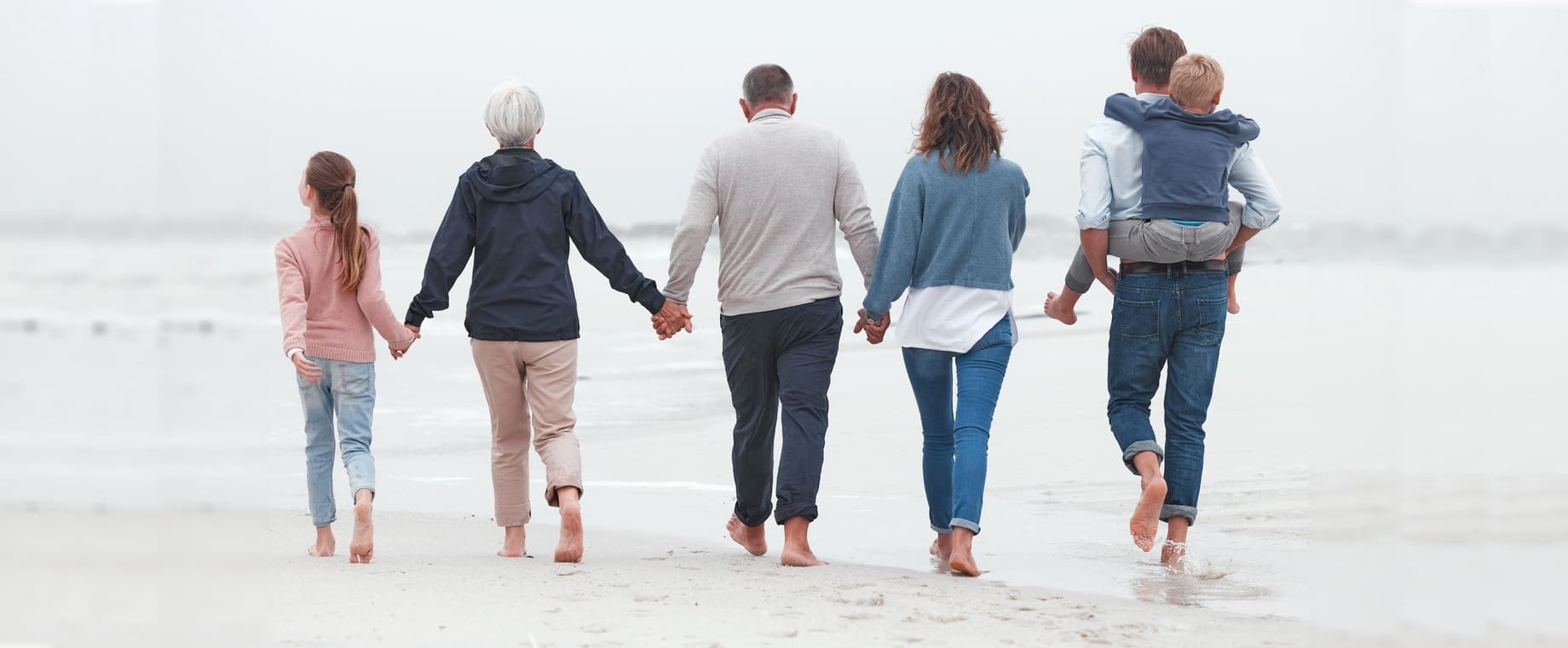 famiglia di spalle che si prende per mano al mare, simbolo dell'alleanza per la salute mentale